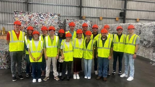 a group of people wearing safety vests and orange helmets