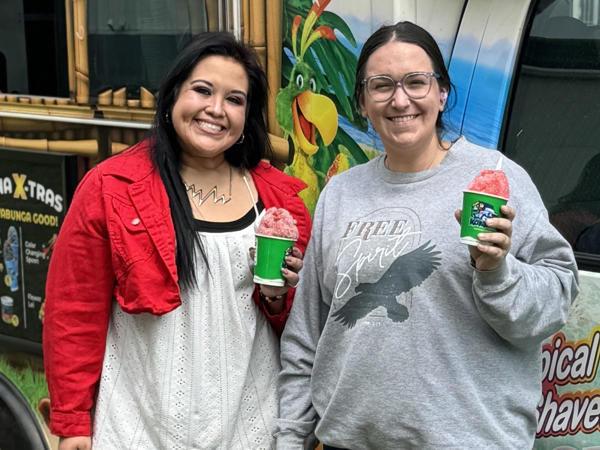 two women standing next to a truck