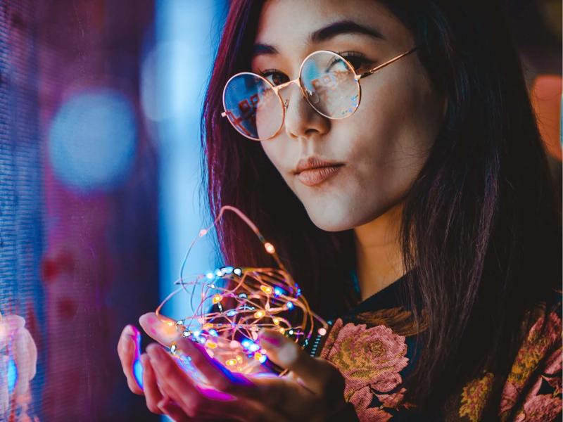 a woman holding a string of lights