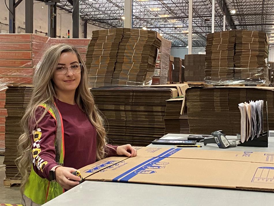 a woman standing behind a table with boxes in a warehouse