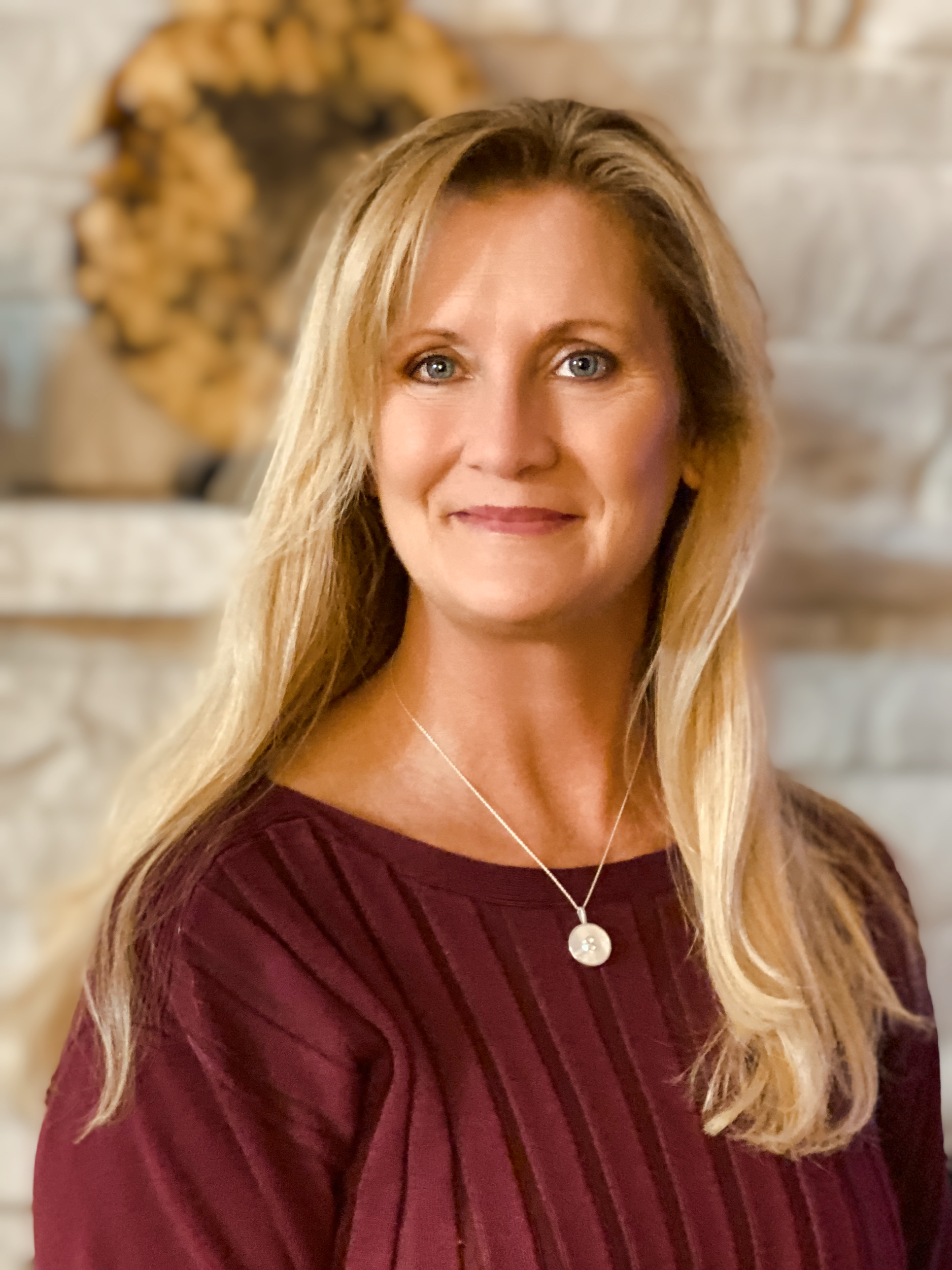 a woman with long blonde hair wearing a maroon shirt