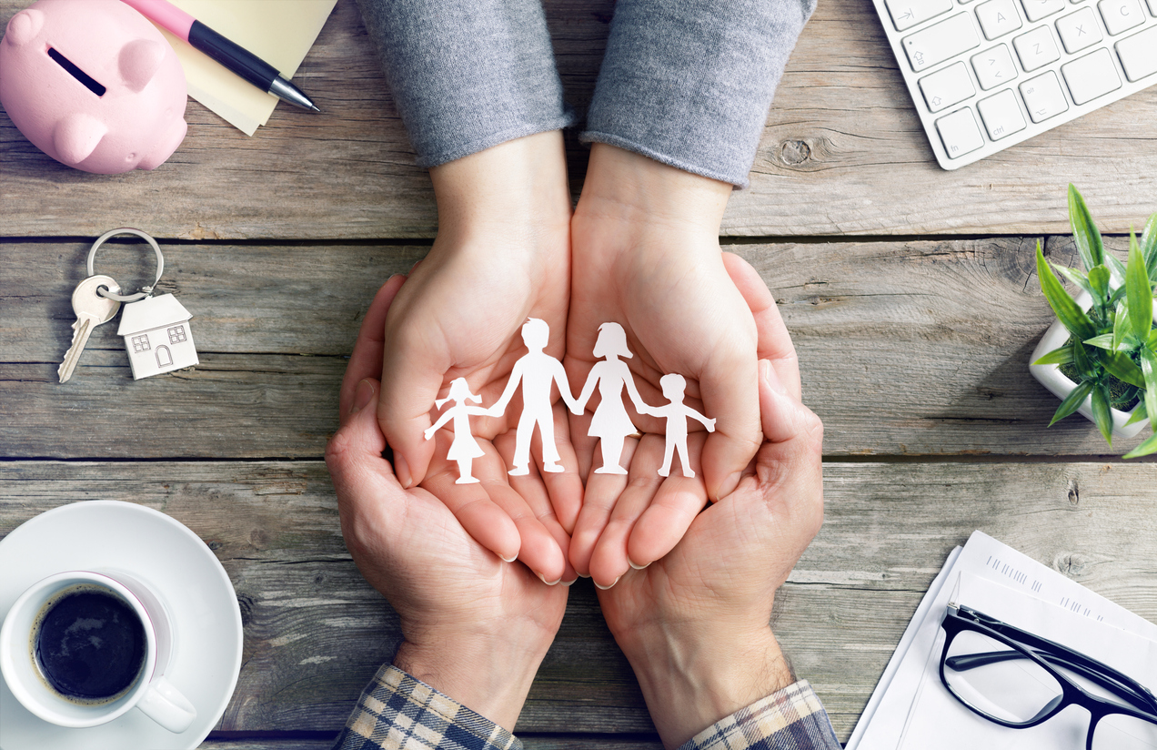 hands holding paper cut out of a family