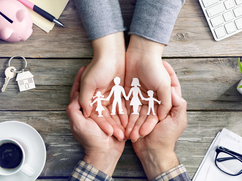 hands holding paper cut out of a family