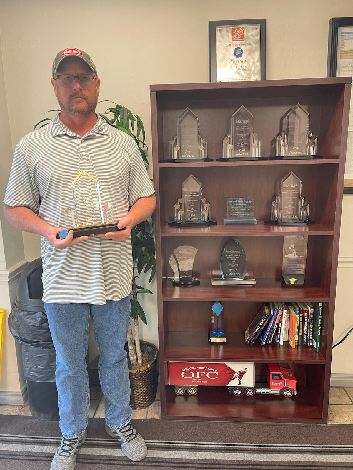 a man standing next to a shelf with trophies