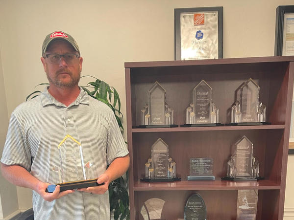 a man standing next to a shelf with trophies