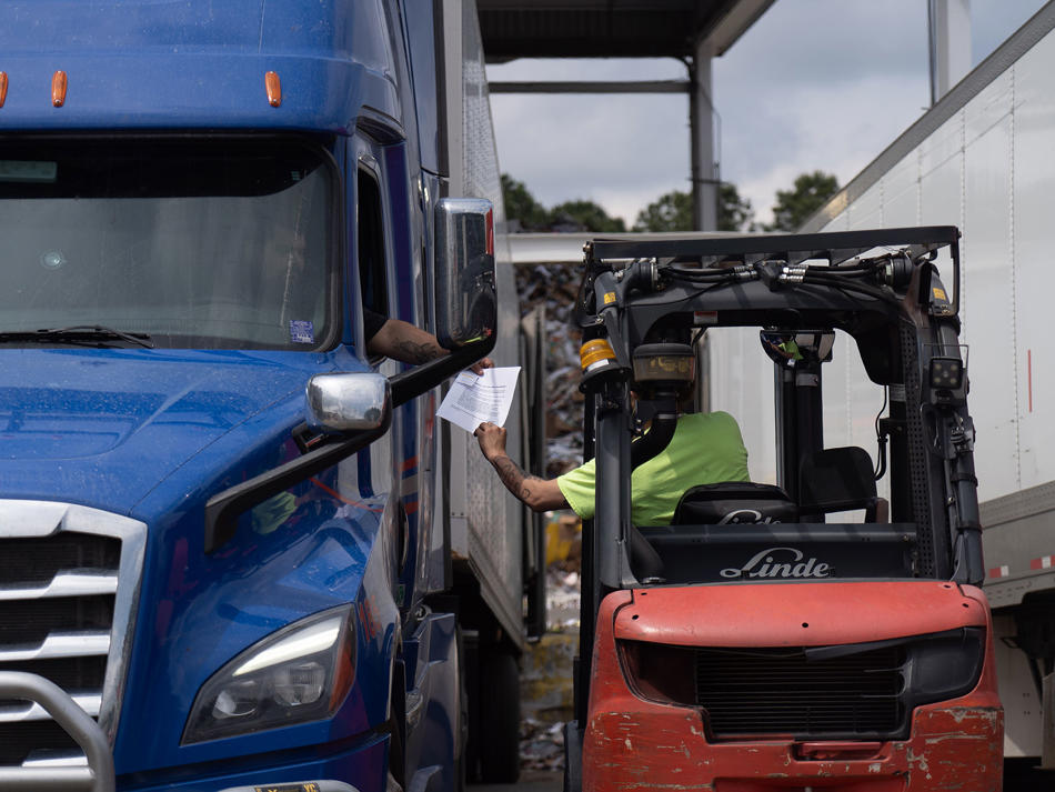 a man in a forklift next to a truck