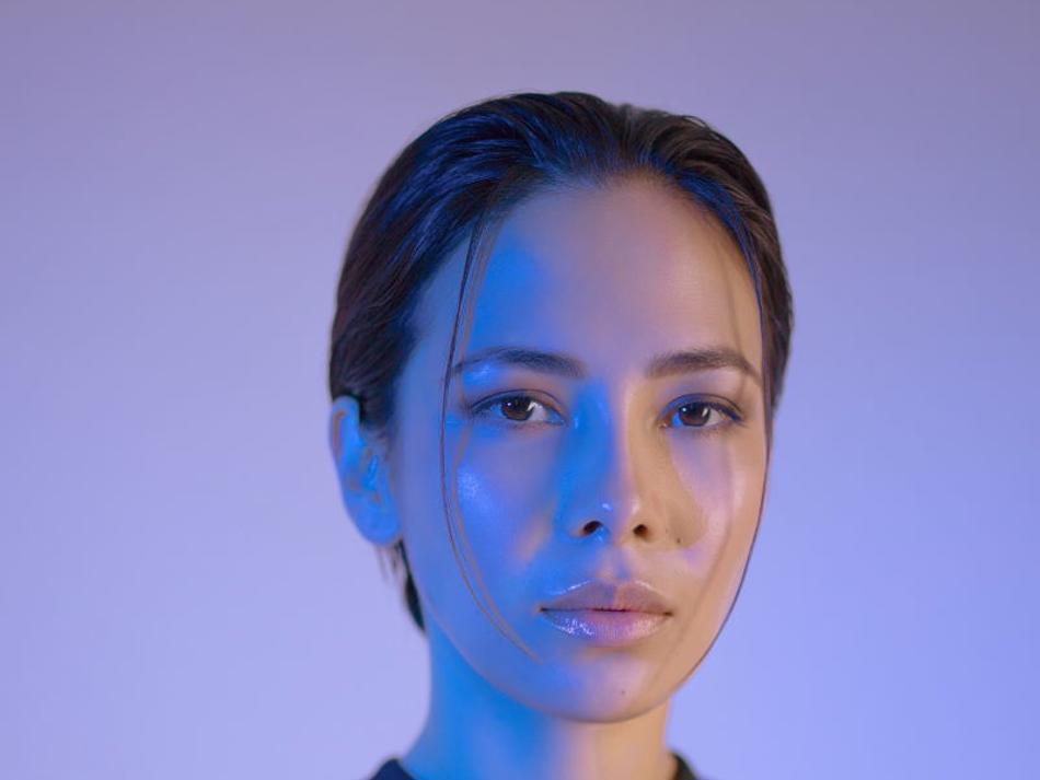a woman with dark hair and a blue light