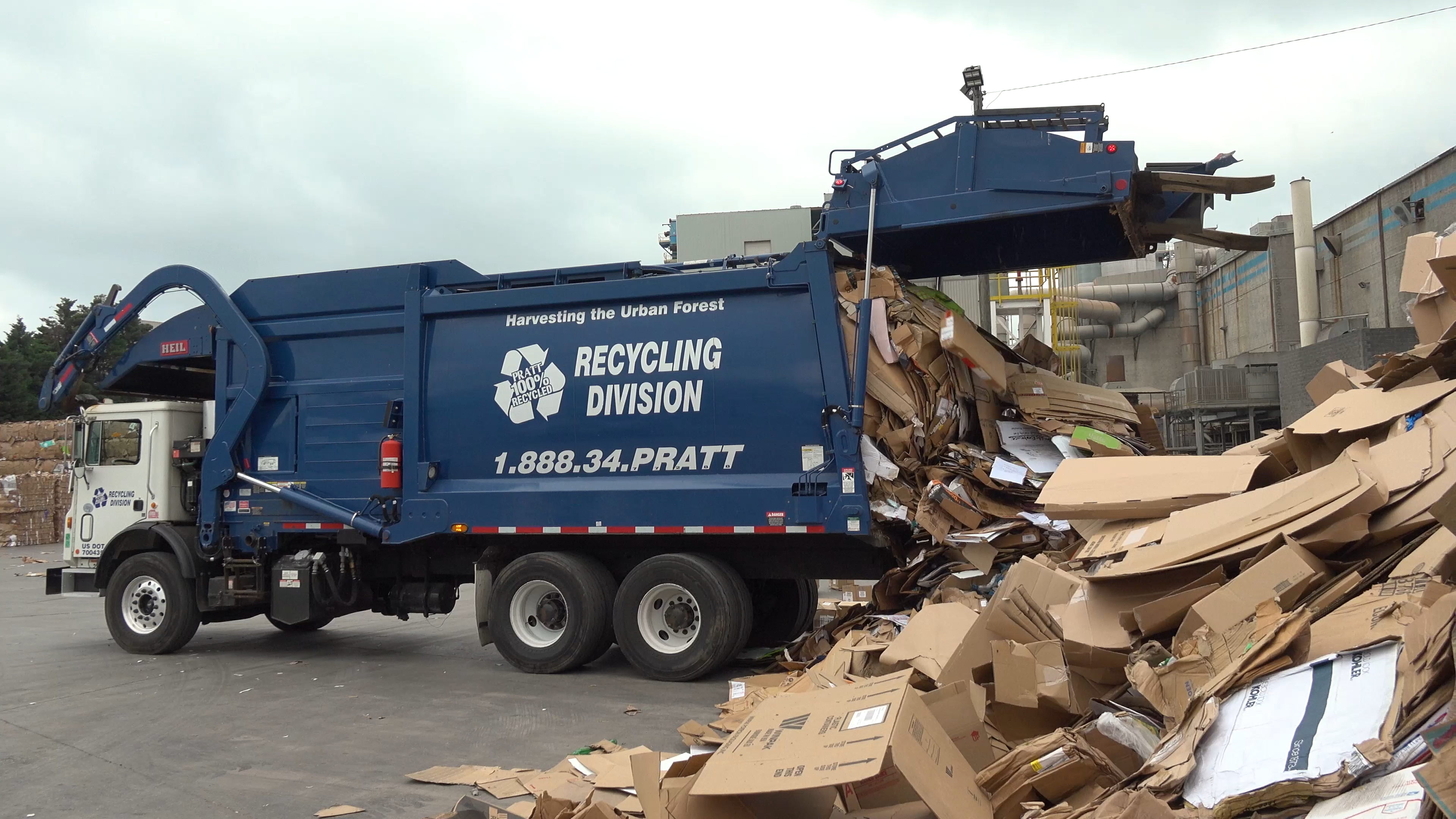 a blue garbage truck with a pile of cardboard boxes