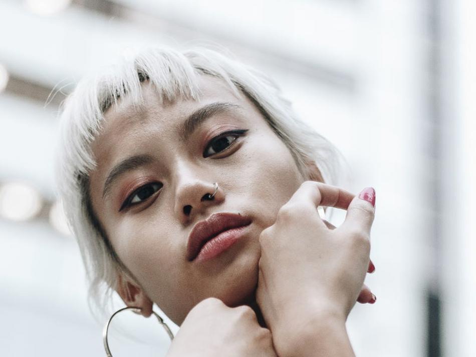 a woman with blonde hair holding her chin