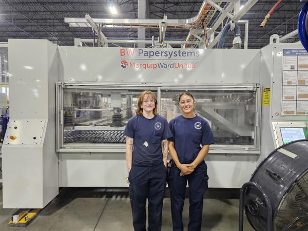 two women standing in front of a machine