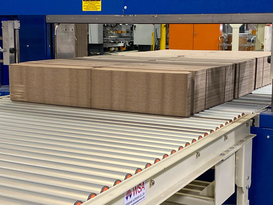 a conveyor belt with a stack of cardboard boxes