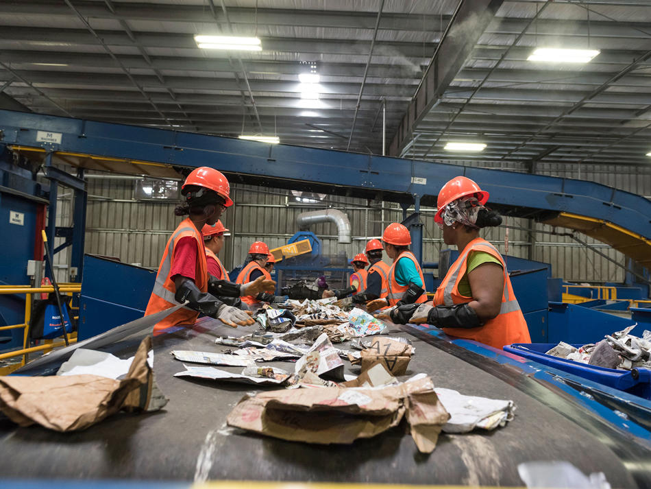 a group of people in orange vests and helmets in a factory