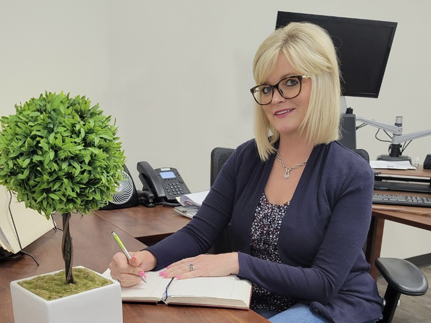 a woman sitting at a desk writing on a notebook